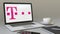 Opening laptop with T-Mobile logo on the screen. Modern workplace conceptual editorial 4K clip