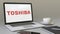 Opening laptop with Toshiba Corporation logo on the screen. Modern workplace conceptual editorial 4K clip