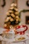 Openwork lantern and two Christmas cups on table against christmas tree lights