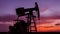 Operating oil and gas well profiled on sunset sky