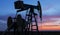 Operating oil and gas well profiled on sunset sky