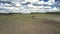 Operating tractor on field against forests under cloudy sky