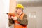 Operator dressed in safety uniform like vest, helmet and safety glasses, drilling a wall with a drill. Concept of work, builder