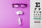 Ophthalmic accessories Glasses and lenses with vision test table for vision correction on a pink background
