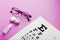 Ophthalmologist accessories glasses, lenses and vitamins with a test target for vision correction on a pink background