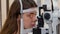 Ophthalmology treatment - a young woman checking her visual acuity with a light of special big optometry machine