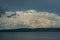 The opposite shore of the azure lake against the blue sky with white clouds.