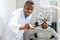 Optician doing optometry eye exam for black african american teen girl patient. Male optometrist with phoropter while examining