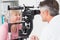 Optician examining senior female patient through slit lamp