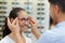 optician fitting glasses on beautiful young woman