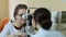 Optician with tonometer examining patient`s eyes