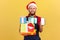 Optimistic deliveryman in uniform and red santa claus hat holding holidays presents and showing smartphone with blank display,