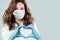 Optimistic doctor woman in protective mask making heart. Healthcare, medicine and treatment concept