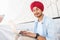 Optimistic Indian handsome guy in red turban pagg using laptop outdoors