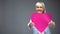 Optimistic retired woman showing big pink heart, cardiology clinic services
