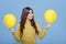 Optimistic stylish girl showing yellow balloons blue background