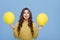 Optimistic stylish girl showing yellow balloons and smiling