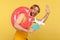 Optimistic tourist guy in undershirt standing with pink donut rubber ring, holding passport document and airplane