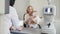 Optometrist checks child`s eyesight - mother and child in ophthalmologist room