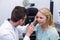 Optometrist examining female patient through ophthalmoscope