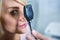 Optometrist examining female patient through ophthalmoscope