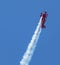 Oracle stunt bi-plane climbing high in sky leaving trail of smoke