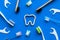 Oral hygiene concept. Tooth drawn with toothpaste near toothbrush, dental floss on blue background top view