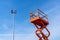 Orang lifting tower climbs up to a street lamp