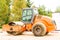 Orange asphalt roller in the parking lot before the start of construction work on laying bitumen. machine for compaction loose