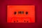 Orange audio cassette on the dark red background