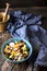 Orange, avocado, blue cheese, chicken and onions salad in a blue bowl on a wooden background.