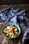 Orange, avocado, blue cheese, chicken and onions salad in a blue bowl on a wooden background.