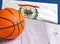 Orange basketball ball with flag West Virginia on wooden parquet. Close-up image of basketball ball over floor in the gym.