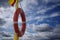 Orange beach lifebuoy on the background of clouds and sky