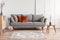 Orange and beige pillows on grey comfortable couch in chic living room interior