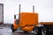 Orange big rig classic old style semi truck driving on highway i