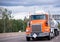 Orange big rig semi truck tractor with two tank trailers transporting fuel on the highway road