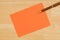 Orange blank greeting card with a pen on textured wood background