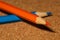 Orange and blue pencils on corkboard is close