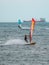 Orange and Blue windsurfing Riding the Waves in a Choppy Sea and Big Boat on Background