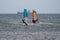 Orange and Blue windsurfing Riding the Waves in a Choppy Sea and Big Boat on Background