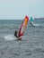 Orange and Blue windsurfing Riding the Waves in a Choppy Sea and Big Boat on Background