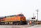 Orange BNSF railroad freight train engine stopped at rural intersection with flagman out inspecting and gate down near Claremore O