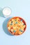 Orange bowl with tiny pancake cereal porridge with milk on a blue background