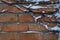 Orange brick wall braided by ivy after snowfall