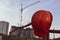 Orange bright helmet hangs on the fence. in the background a construction gantry crane for moving heavy objects to tall buildings