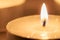 Orange burning candle with wooden background macro