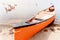 A orange canoe resting on a lakeshore in  public park on summer days