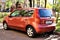 Orange car Nissan Note, rear side view. Photography of a modern hatchback parked in yard