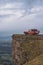 an orange car stands on the very edge of a cliff